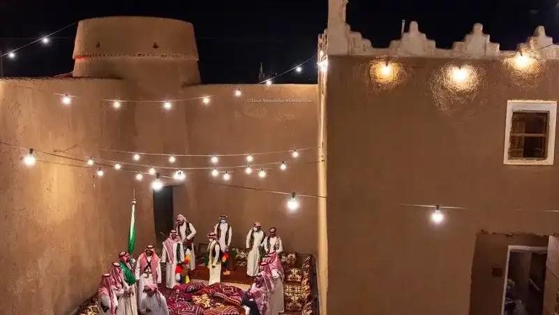 مجلس مسائي في فناء طيني تحت حبال الإنارة
