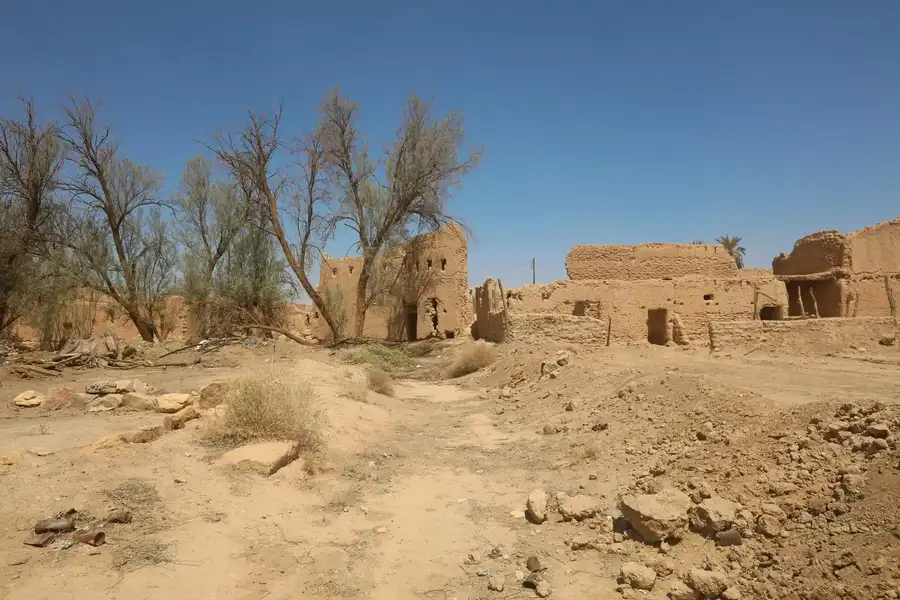 درب ترابي بين أطلال البيوت الطينية وأشجار الأثل