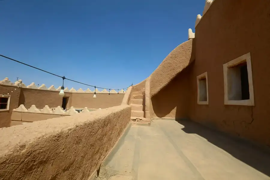 سطح طيني مرمم بشرفات مسننة ودرج يصعد إلى السطح العلوي